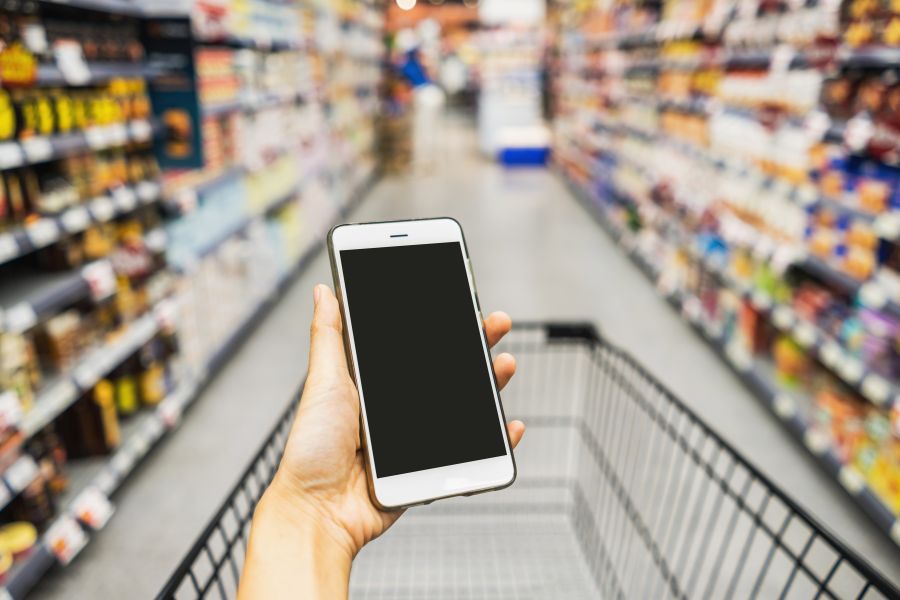 Ich-Perpektive, die auf ein Smartphone im Supermarkt blickt